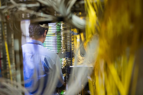Close-up of technician checking routers in server room